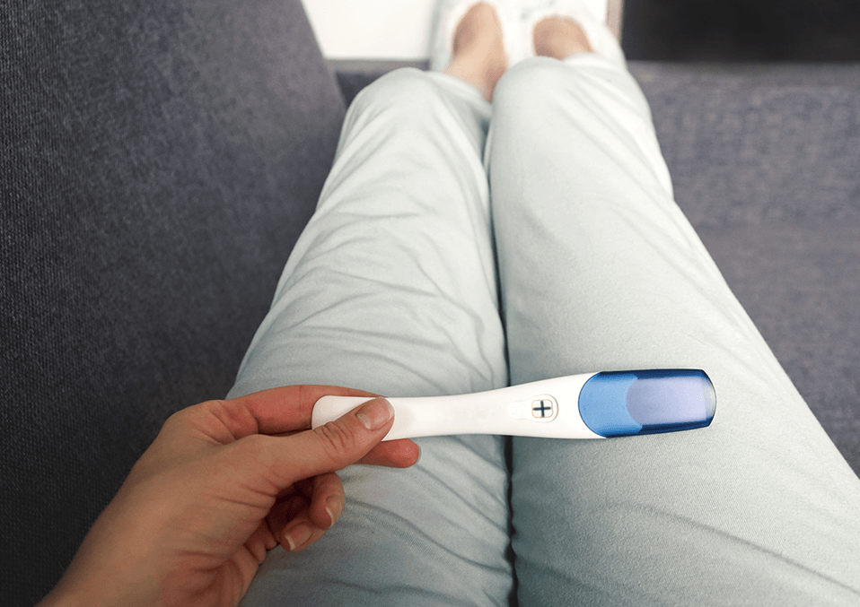 A WOMAN HOLDING A PREGNANCY TEST STICK