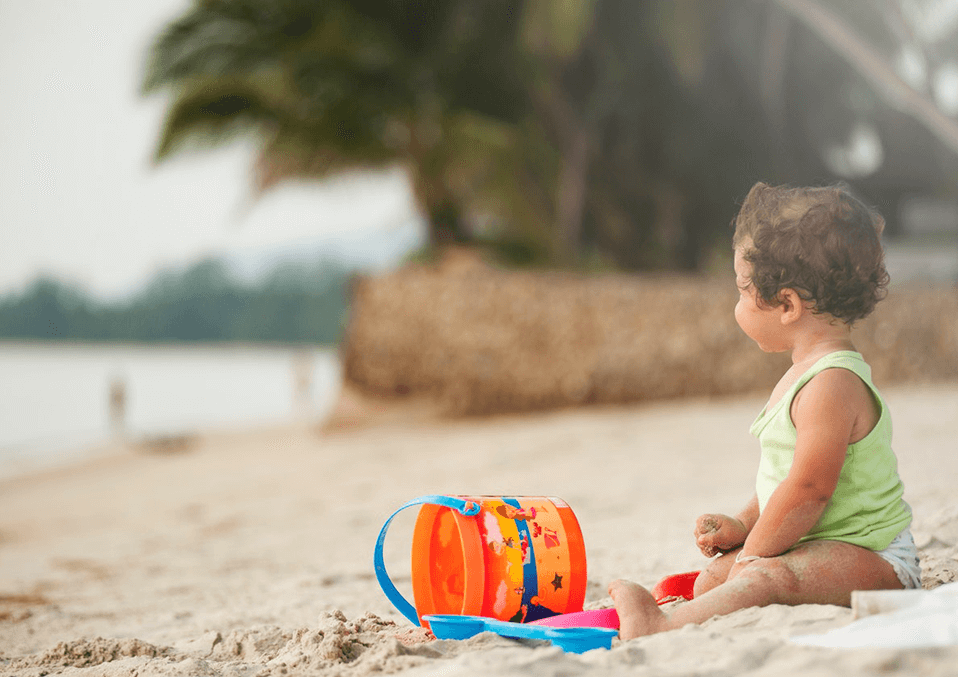 baby standing next to the beach