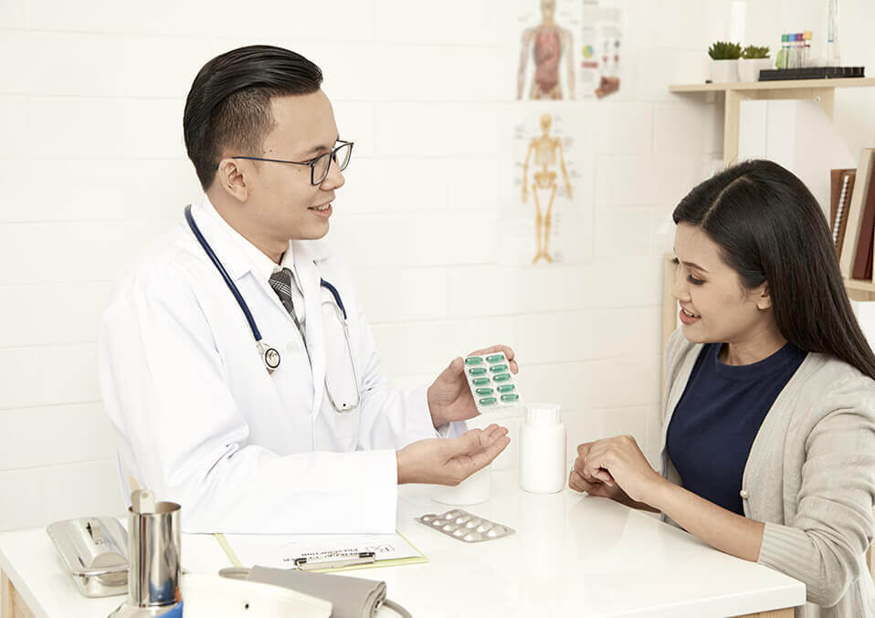 pills and a pregnant woman talking to a doctor